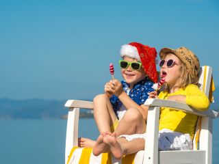A Man And Woman Wearing Santa Hats And Sitting On A White Railing